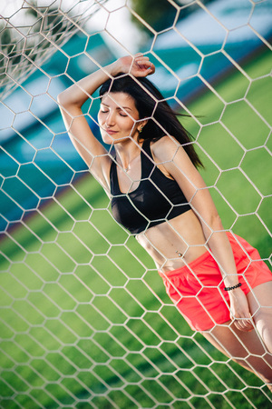 Sport girls posed near football goal. Sexy young woman do sport exercises in sexy sport wear.の写真素材