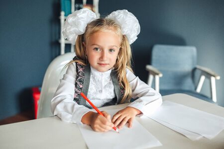 Portrait of cute schoolgirl sitting and drawing
