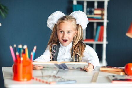 A girl in a school uniform looks at a textbook with a surprised faceの写真素材