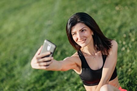 Cute girl taking a selfie with their phone while they do some yoga at a park.の写真素材