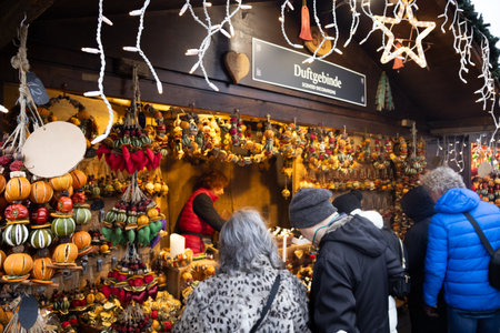 People buy goodies, dried fruits, sweets, and decorations at a Christmas market, enjoying the warm, festive atmosphere.の写真素材