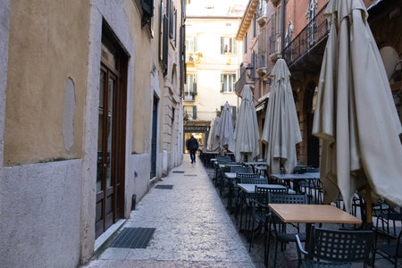 Coffee terrace with tables and chairs in a narrow street in Verona, offering a cozy spot for relaxation and coffee in a charming urban setting.の写真素材