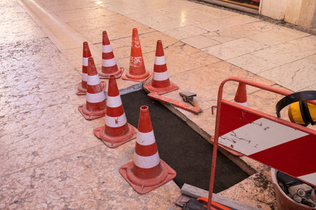 Traffic cones placed around an open manhole, warning of potential danger due to sewer repair work on...