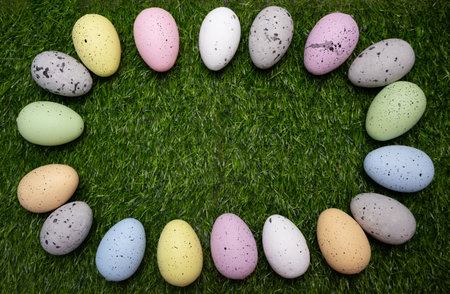 Easter frame of pastel colorful eggs on grass, perfect for a spring-themed greeting card or...