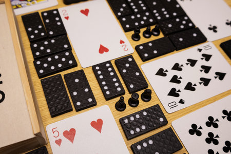 Playing background with domino pieces, playing cards, and chess arranged on a wooden surface
