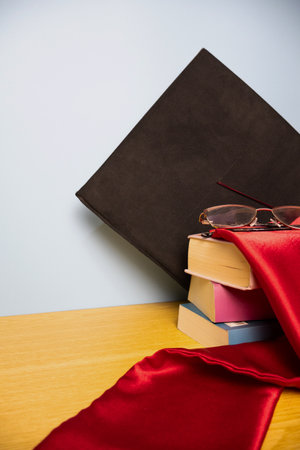 Vertical background featuring an academic hat, graduation stole, and a stack of booksの写真素材