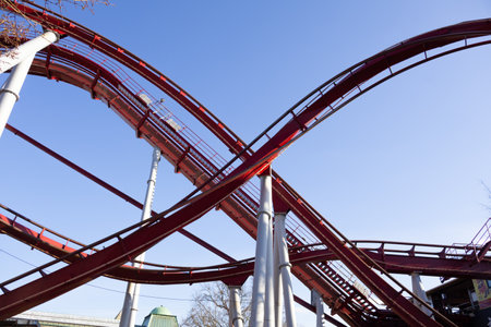 Roller coaster in an amusement park against a bright blue sky, capturing the thrill and excitement of the ride.の写真素材
