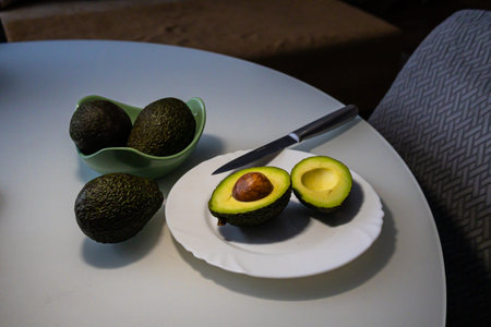 Avocado fruits on a white plate with a knife on the table