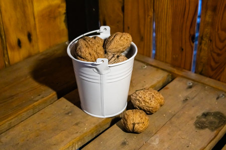 Whole walnuts in a white bucket on a wooden background.