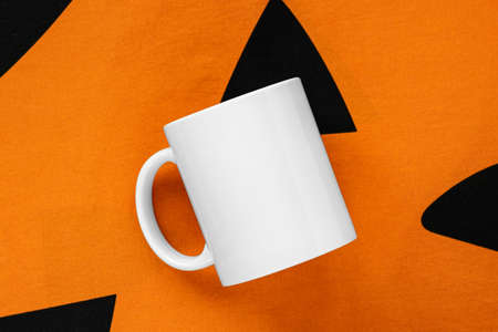 A mockup of a white mug in an autumn Halloween settingの写真素材