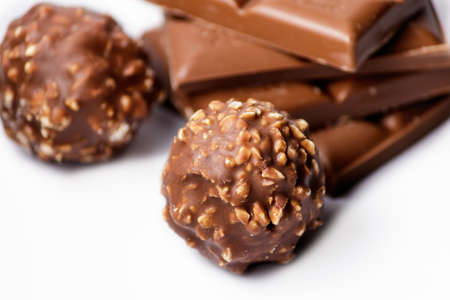 A top view of chocolate candy balls with chocolate bars on a white surfaceの写真素材