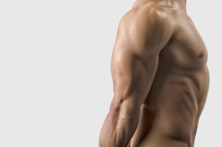 Strong bodybuilder man with perfect abs, shoulders,biceps, triceps and chest, personal fitness trainer flexing his musclesの写真素材