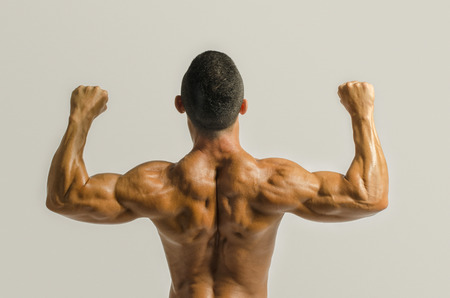 Bodybuilder showing his back and biceps muscles, personal fitness trainer. Strong man flexing his musclesの写真素材
