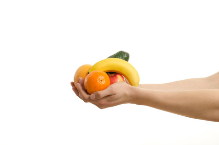 Hand offering a bunch of organic fruits, banana, orange, avocado,apple isolated on whiteの写真素材