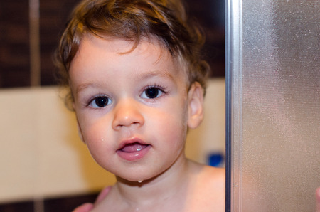Portrait of a baby taking a bath. Cute toddler in the shower with wet face.の写真素材