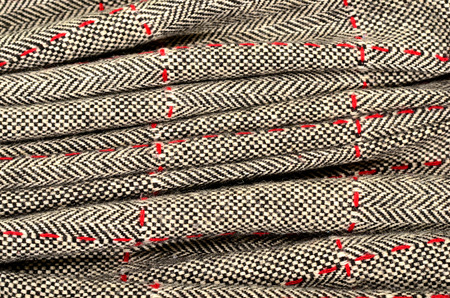 Wool fabric with red sewing and a leather triangle. Tartan design as background. Checked fabric.の写真素材