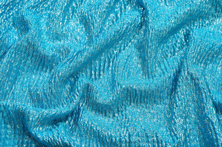 Crumpled blue and silver sparkly textured fabric.の写真素材
