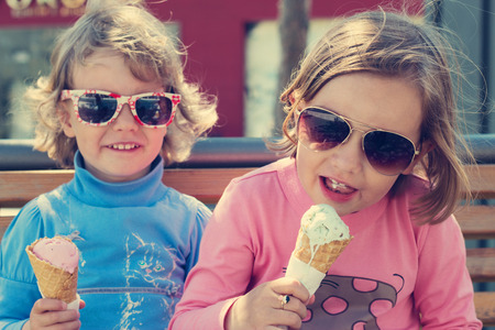 Two little girls sisters eating ice cream.の写真素材