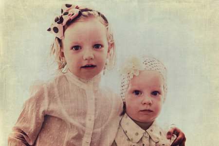 Art photo. Portrait of beautiful little girls sisters in vintage style. The image is tinted, blurring and selective focus.の写真素材