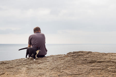 Man and cat sitting on the beach. Selective focus.の写真素材