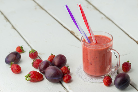 Strawberry plum smoothie in a glass with a straw. Selective focus.の写真素材