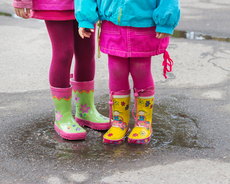 Children's feet in rubber boots in a puddle after rain. Selective focus.の写真素材