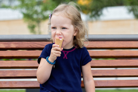 Funny little girl (3 years) eat ice cream. Selective focus.