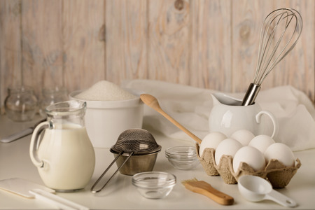 Kitchen utensils and tools for homemade baking on a light wooden background. Selective focus.