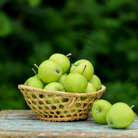 Homemade rustic green apples in a basket on an old stool. Selective focus.の写真素材