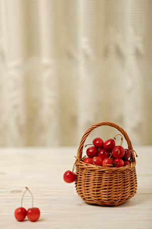 Cherries in a basket on a light wooden background. Selective focus.の写真素材