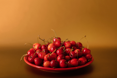 Cherries on a red plate on a gold background. Selective focus.の写真素材