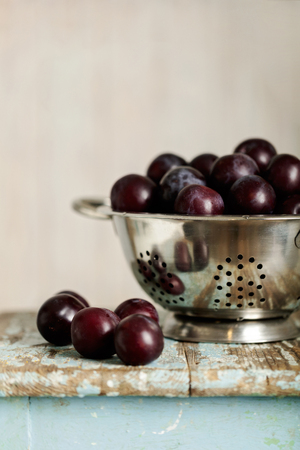 Ripe plums in a colander on a wooden background. Selective focus.の写真素材