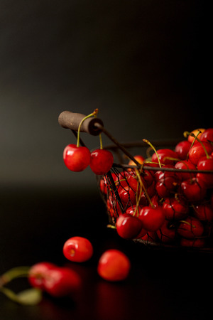 Cherries in a metal basket on a black background. Selective focus.の写真素材