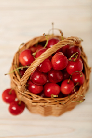 Cherries in a basket on a light wooden background. Selective focus.の写真素材