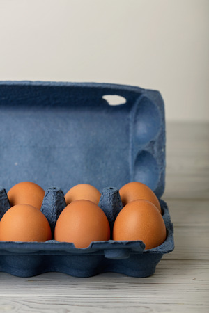 Chicken eggs in a blue package on a gray wooden background. Selective focus.