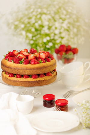 Homemade strawberry cake on a glass stand on the white background. Selective focus.の写真素材