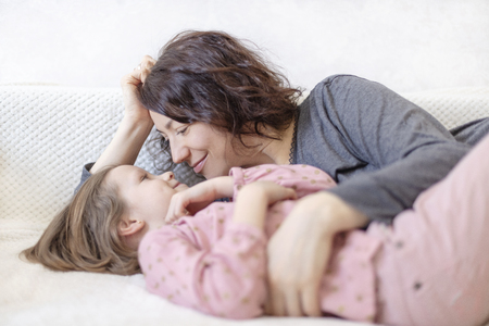 Young woman with her daughter are resting on the sofa. Selective focus.の写真素材