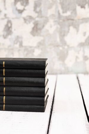 Stack of old ancient shabby books on a white wooden background. Selective focus.の写真素材