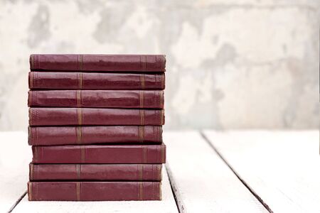 Stack of old ancient shabby books on a white wooden background. Selective focus.の写真素材