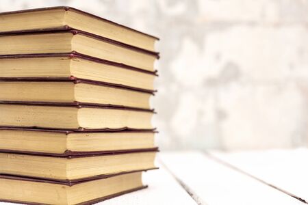 Stack of old ancient shabby books on a white wooden background. Selective focus.の写真素材