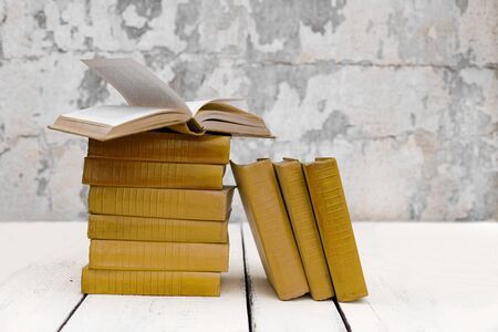 Stack of old ancient shabby books on a white wooden background. Selective focus.の写真素材