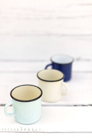 Enameled mugs in retro style on an old wooden background. Selective focus.の写真素材