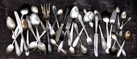 Vintage cutlery - spoons, forks and knives on an old woodenの写真素材