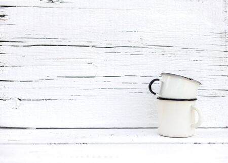 Enameled mugs in retro style on an old wooden background. Selective focus.