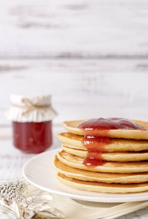 Tasty breakfast. Pancakes with strawberry confiture and butter. Selective focus.