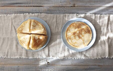 Cooking pancakes. Shrovetide (Maslenitsa) - blini stack on a blue plate on a wooden table. Selective...