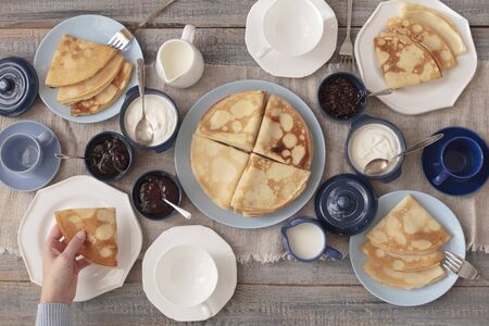 Shrovetide (Maslenitsa) - breakfast with blini stack, jam and sour cream with tea or coffe on bare plates on a wooden table. Selective focus.の写真素材