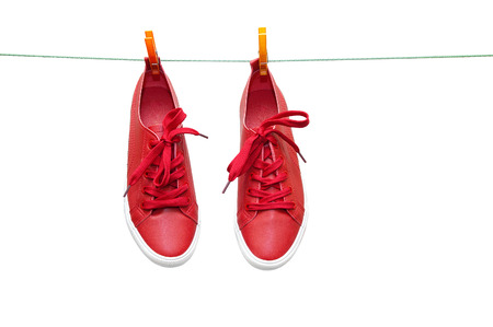 Red sneakers hang on clothespins on a rope. Close-up.の写真素材