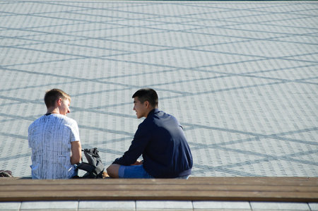 Novosibirsk 07-31-2018. Two young guys are sitting on a park bench.のeditorial素材