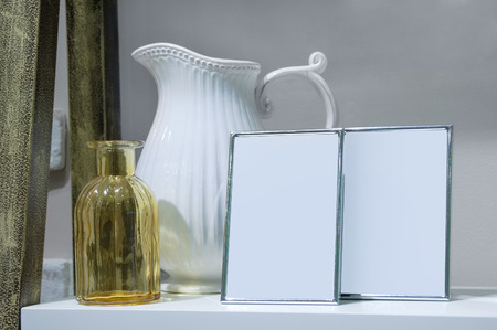 Frames for a photo, a jug, a glass bottle. On the shelf in the interior of the house.